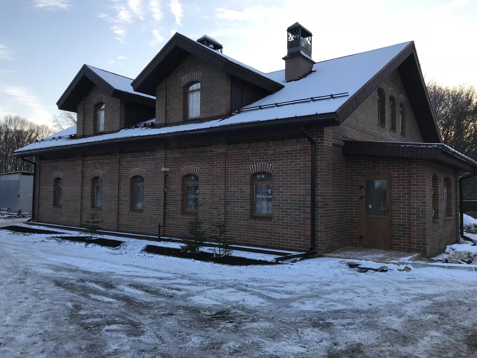 Готовый кирпичный дом с тремя мансардными окнами зимой