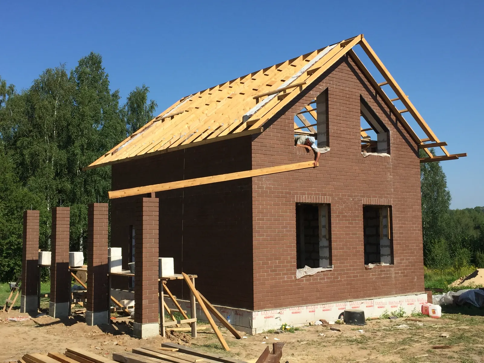 Кирпичный дом на этапе тёплого контура: стены возведены, стропила смонтированы